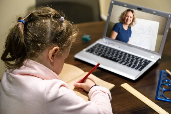 Kid virtual learning with teacher by laptop, little girl studies online in room, tutor teaches preschool child during quarantine. Concept of distance lesson, home education and elearning technology.