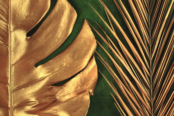 golden palm and monstera leaves on dark green background