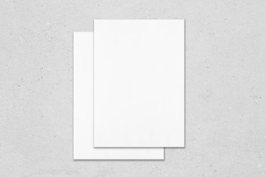 Gri conc üzerinde üst üste yatan iki boş poster mockups