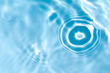 Bulanık mavi, berrak, durgun su yüzeyi dokusu sıçrama ve kabarcıklarla kaplı. Moda soyut doğa geçmişi. Güneş ışığı altında su dalgaları kopyalama alanı ile.