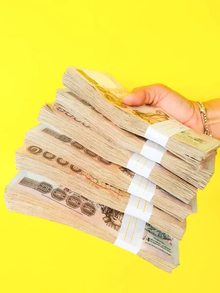 Thai bank note stack young woman holding on a yellow background