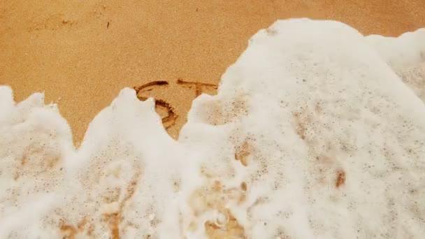 Krásné hvězdné písmo namalované na teplém písku smývá mořskou vodu za slunečného dne.