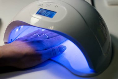 Elektrikli cihaz makine kullanarak donanım manikür. tırnak cilası uygulamadan önce çivi hazırlanması için yordam. Elinde manikürcü mavi eldiven ve istemci çivi. Kadın Güzellik Salonu. 