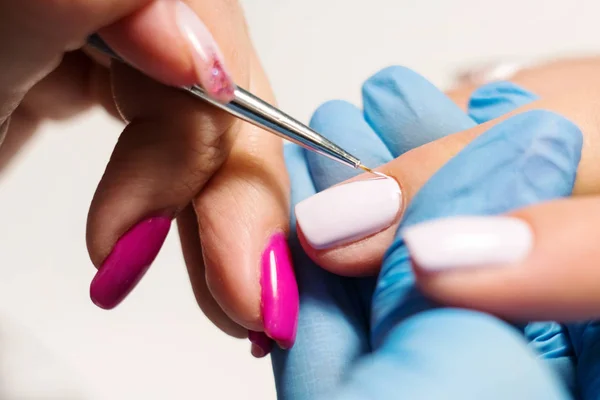 Hardware Manicure using electric device machine. procedure for the preparation of nails before applying nail polish. Hands of Manicurist in blue gloves and Nails of Client. Woman In Beauty Salon.