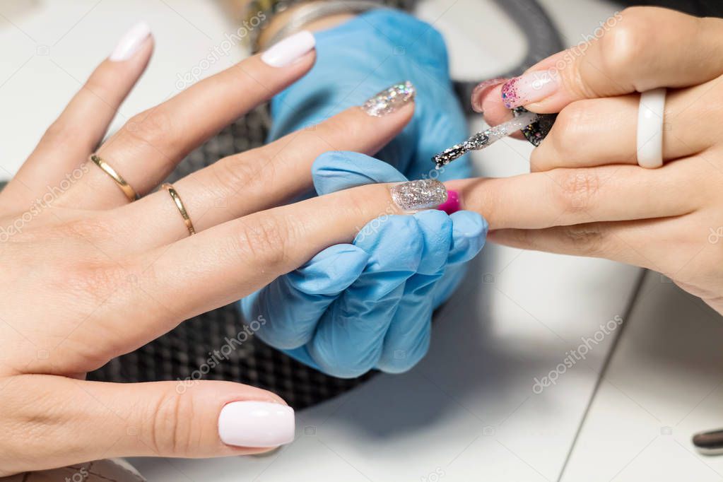 Hardware Manicure using electric device machine. procedure for the preparation of nails before applying nail polish. Hands of Manicurist in blue gloves and Nails of Client. Woman In Beauty Salon. 