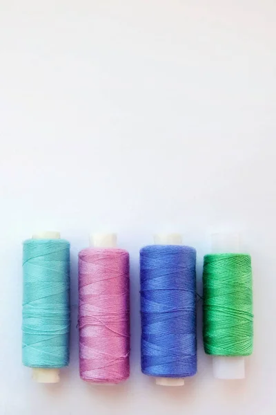 Multicolored thread coils on pink blue background. Sewing supplies and accessories for needlework, stitching, embroidery. space for text. flat lay, top view