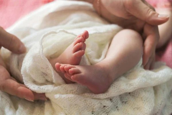 Baby feet in mother hands. Mom and her Child. Happy Family concept. Beautiful conceptual image of Maternity. Feet of a newborn baby.