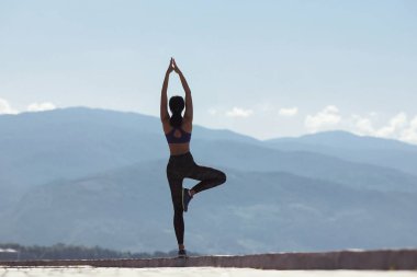 Karşı dağlar deniz kenarında sahildeki sabah yoga yaparken kız.