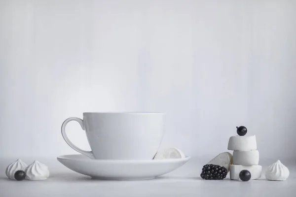 Cup of coffee, white background. Marshmallows, blue, black berries. Blueberries, blackberries, black currants.