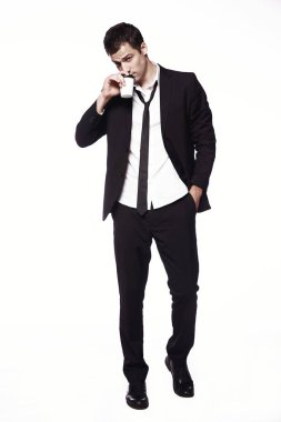 Bir kahve fincanı beyaz bir arka plan üzerinde siyah elbiseli Genç bir adam. Reklam, yaratıcılık. Kahve.