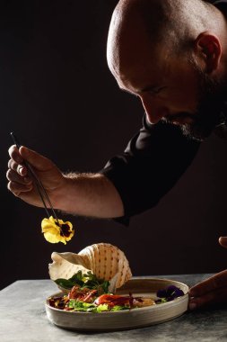 Şef deniz ürünleri ve sebzelerden oluşan bir salata hazırlar..