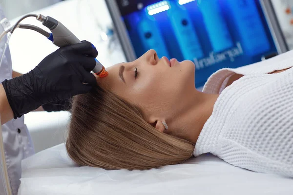 Side view of woman receiving microdermabrasion therapy on forehead at beauty spa — Stock Photo, Image