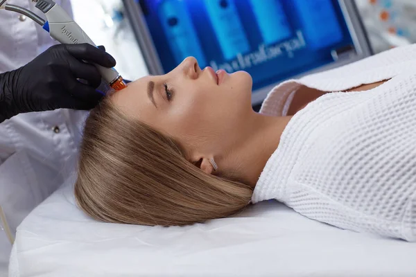 Side view of woman receiving microdermabrasion therapy on forehead at beauty spa — Stock Photo, Image