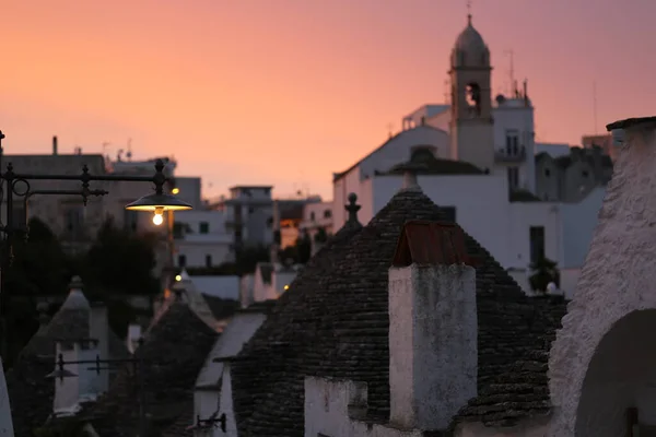 Alberobello şehri; Trulli UNESCO dünya mirası kasabası eşsiz taş duvarları, koni çatıları, gün batımında beyazlatılmış evler,
