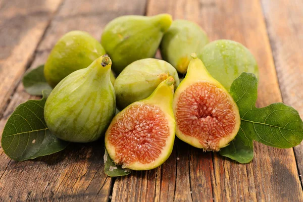 close-up photo of fresh fig and leaves on wooden table