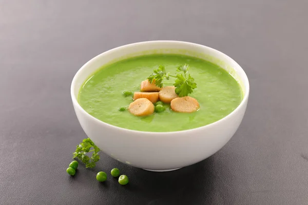 Soup with green peas in white bowl