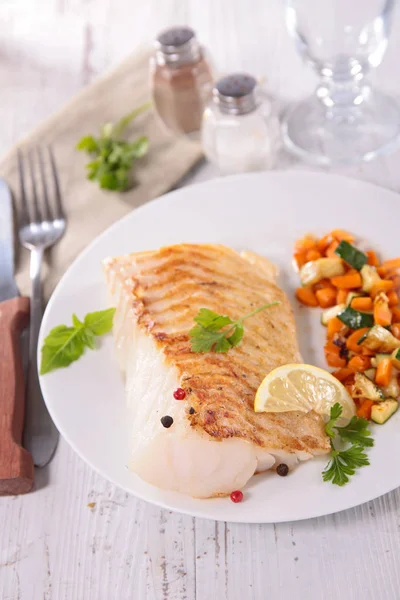 fish fillet cooked with vegetables in white plate