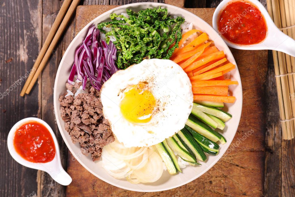 top view of bibimbap with vegetables, beef and eggs