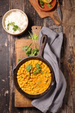 Krema, köri ve ahşap tahta üzerinde tavada otlar ile nohut