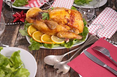 Fırında tavuk portakal dilimleri ve dekore edilmiş masada yeşil salata ile servis