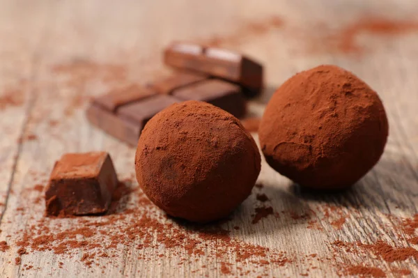 Appetizing chocolate truffle balls with chocolate on wooden background