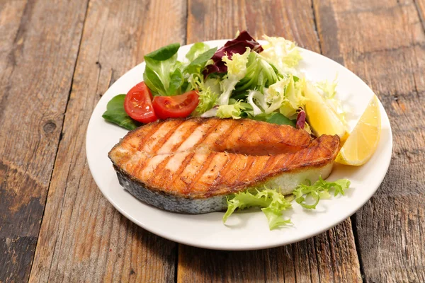 İştah açıcı ızgara somon steak salata ahşap arka plan üzerinde