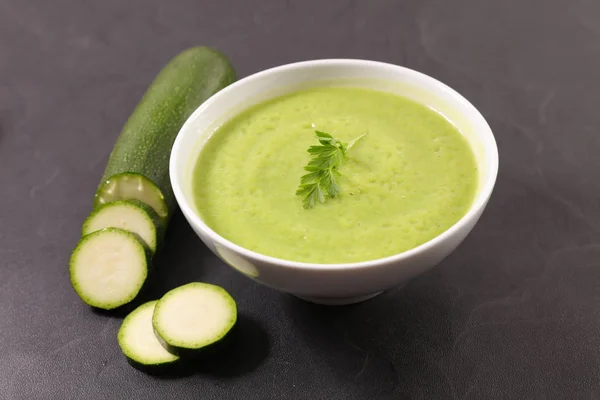 Bowl of creamy green soup and sliced zucchini