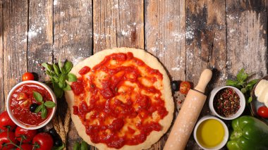 Domates soslu ve malzemeli çiğ hamur pizza.