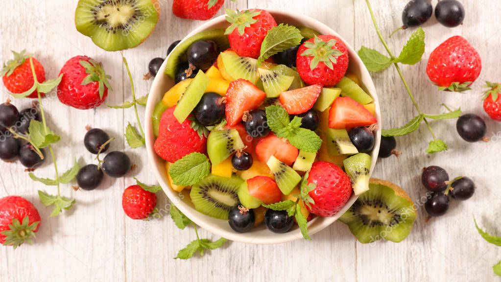 mixed fruit salad in bowl on wooden table