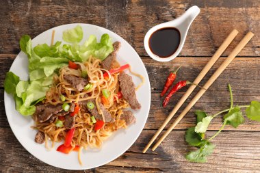 sığır eti ile tavada kızartılmış erişte yemek çubukları ve soya sosu ile servis