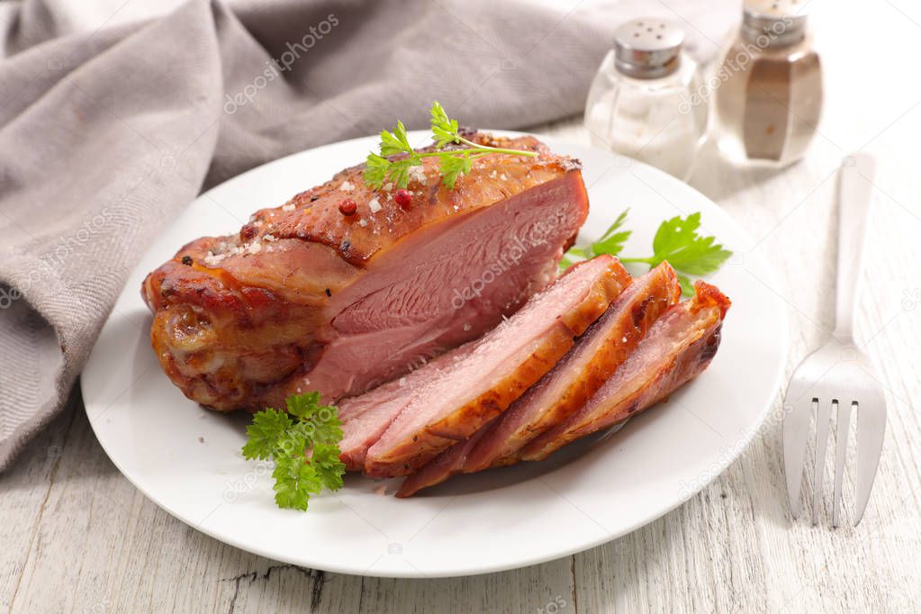 glazed ham sliced with herbs on white plate