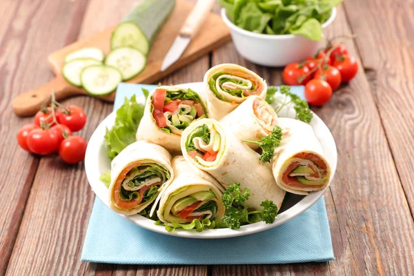 Burrito wraps with tomatoes and green leaves on plate