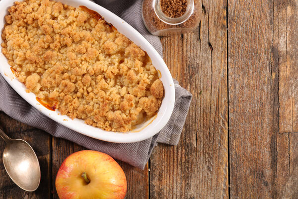 Ceramic pan of apple crumble pie on wooden rustic table