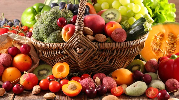 assorted fruits and vegetables in basket on wooden table, still life