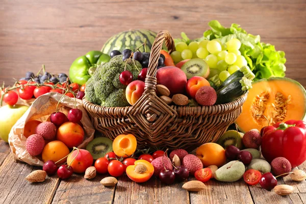 assorted fruits and vegetables in basket on wooden table, still life