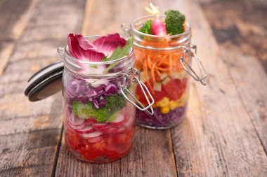 ahşap masa üzerinde cam kavanozlara karışık sebze salatalar