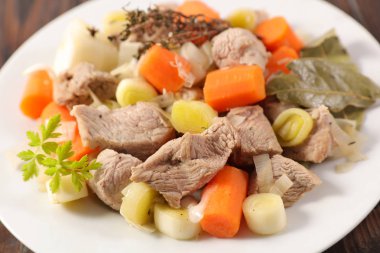 Beyaz tabakta havuç ve pırasa ile Dana