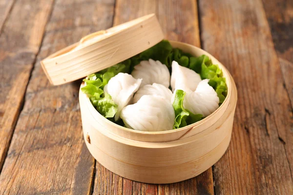 dim sum and lettuce in wooden bowl