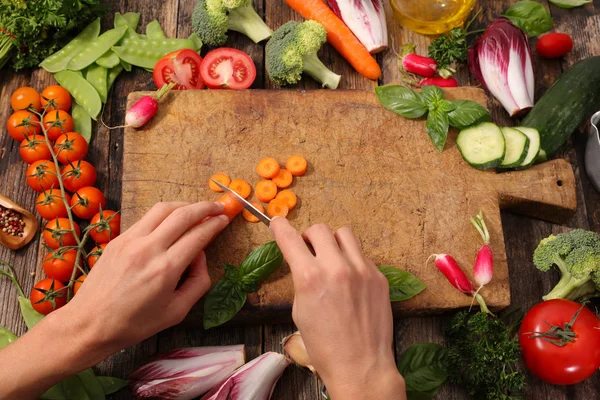 Kadın yemek pişiriyor, çiğ sebze kesiyor.