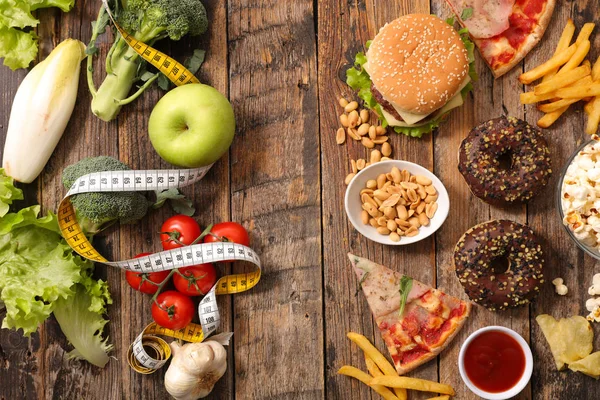 Ahşap masada fast food ve pasta karşı sağlıklı beslenme üst görünümü 