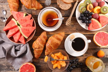 Kahve fincanı, çay fincanı, kruvasan ve taze meyve ile nefis bir kahvaltı.