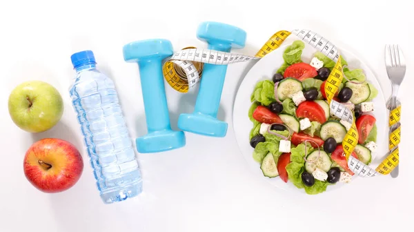 vegetable salad with dumbbell, water, apple and meter tap on white background- diet food concept