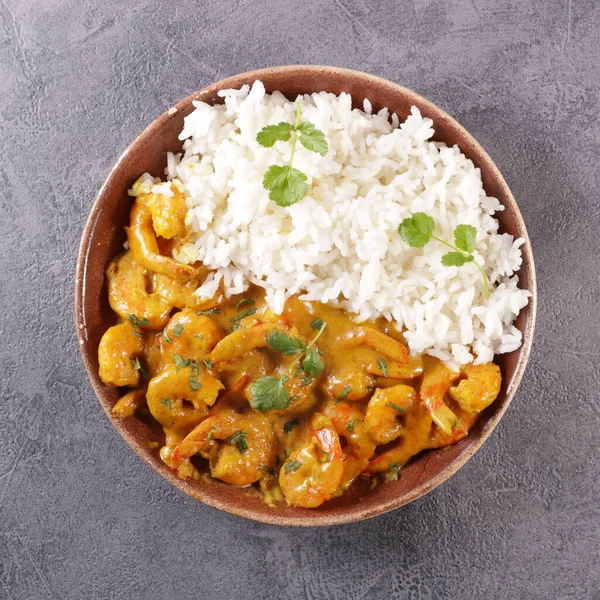 Köri sosu ve pilavla pişirilmiş karides.