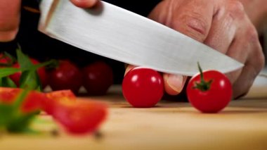 Tahtada kiraz domatesi kesen adama yaklaş.