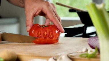 Adam mutfakta taze kırmızı domates kesiyor.