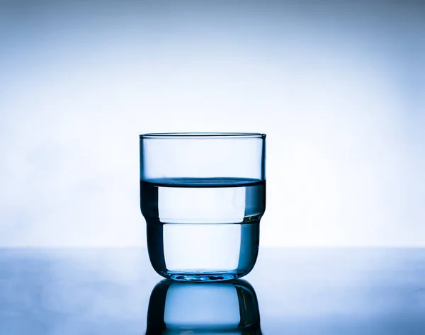 Glass of water on a blue background. Water  into glass on   smok