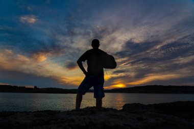 Gün batımı/ Gündoğumu silueti Comino Adası'nda deniz kaya üzerinde