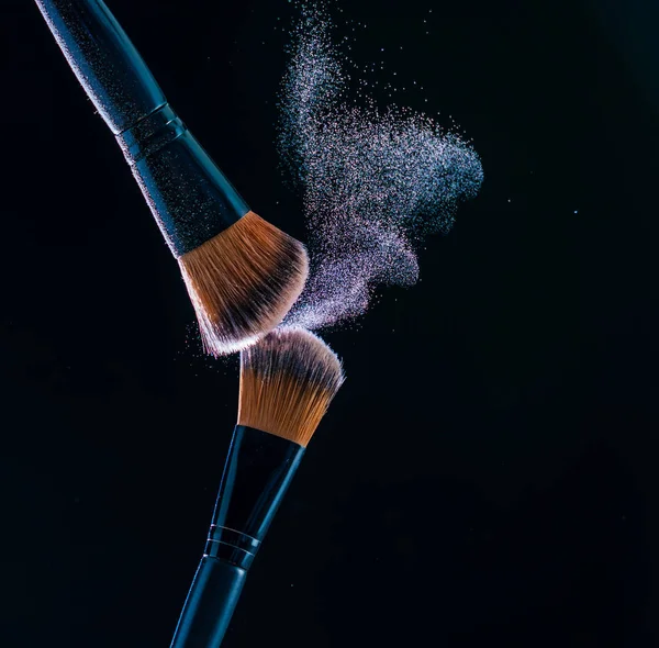 Make up brush with  powder explosion on black background