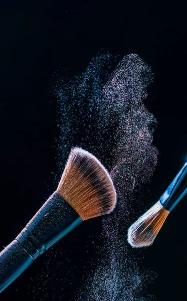 Make up brush with  powder explosion on black background