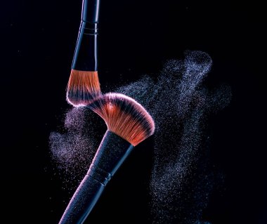 Siyah arkaplanda barut patlaması ile makyaj fırçası